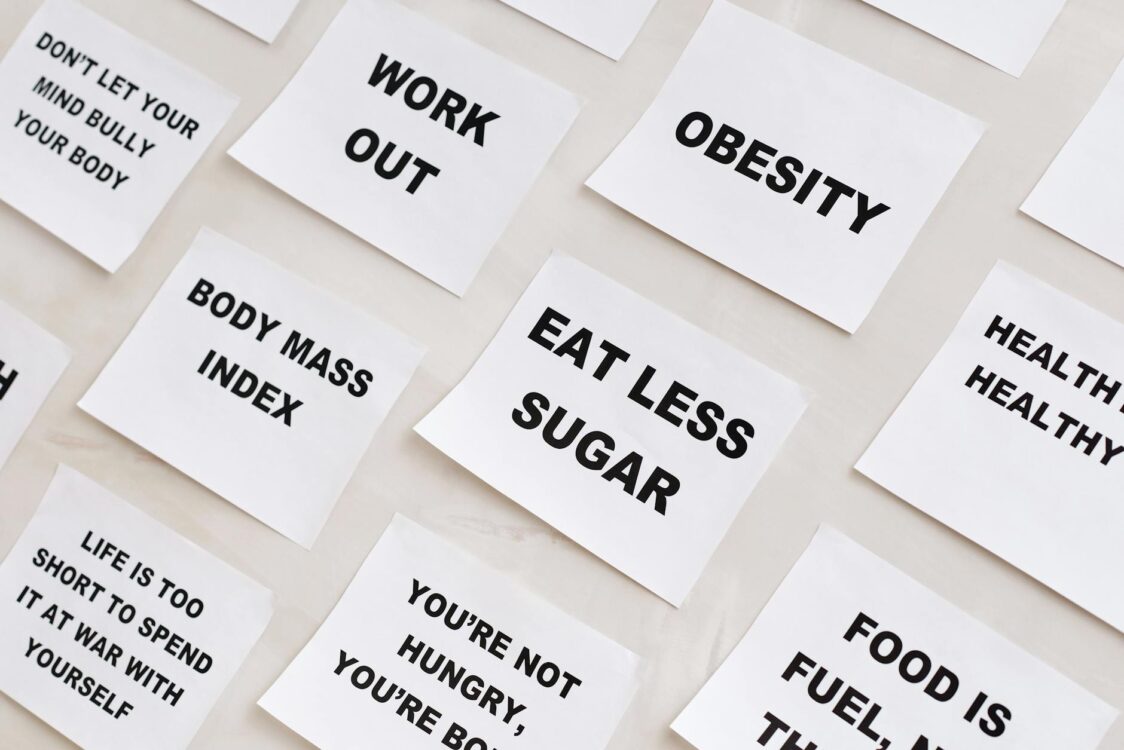 white papers with message that say obesity, eat less sugar, work out.