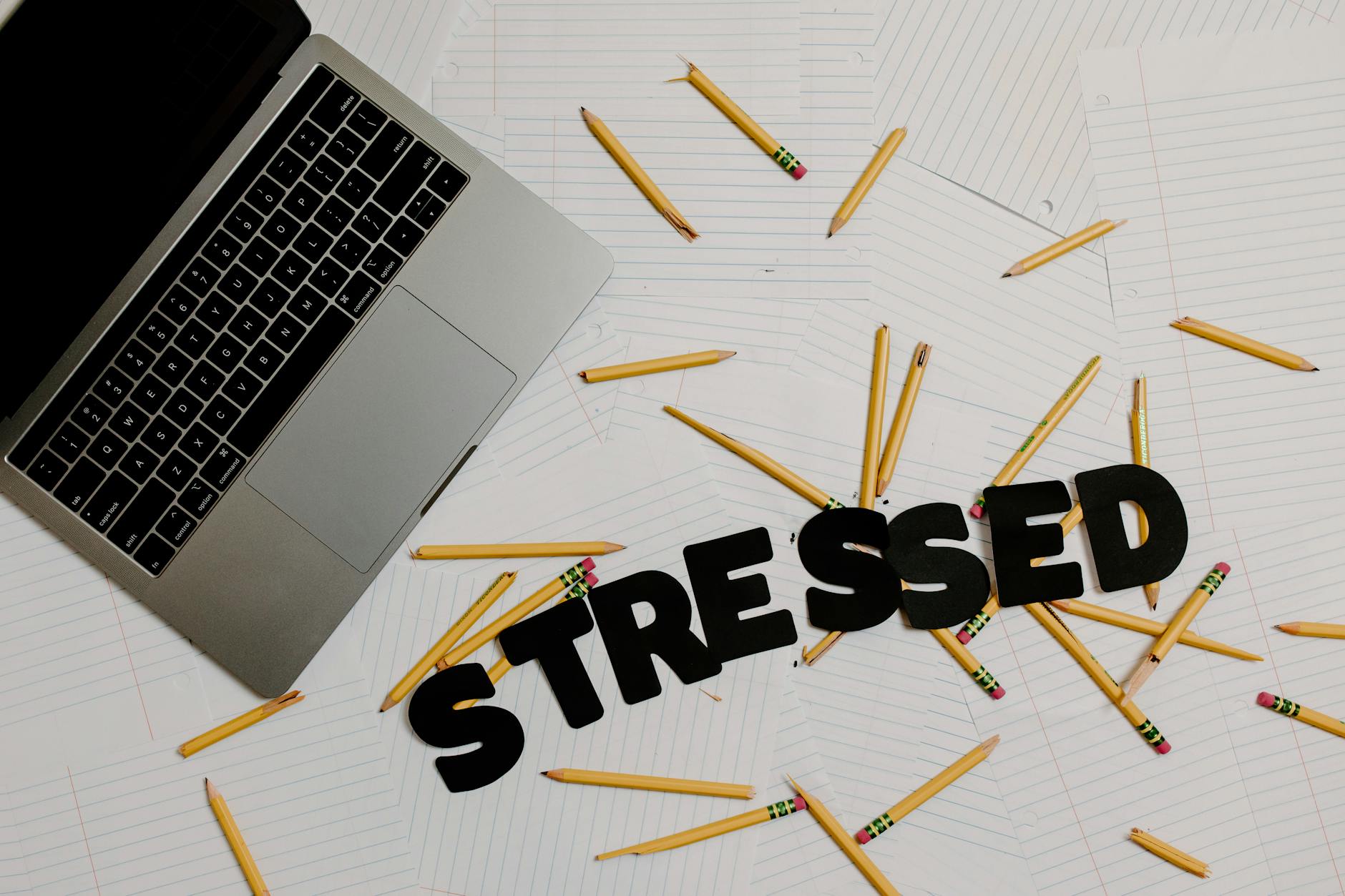 word stressed and pencils on table near laptop